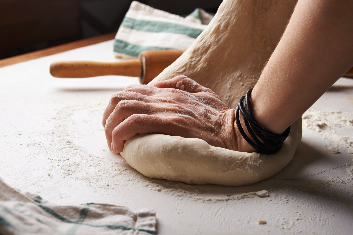 Hands kneading fresh pasta dough on a floured board